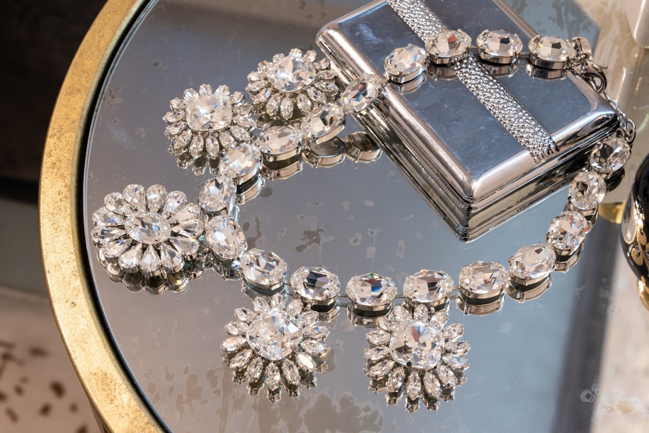 A floral, crystal necklace lying on a glass table