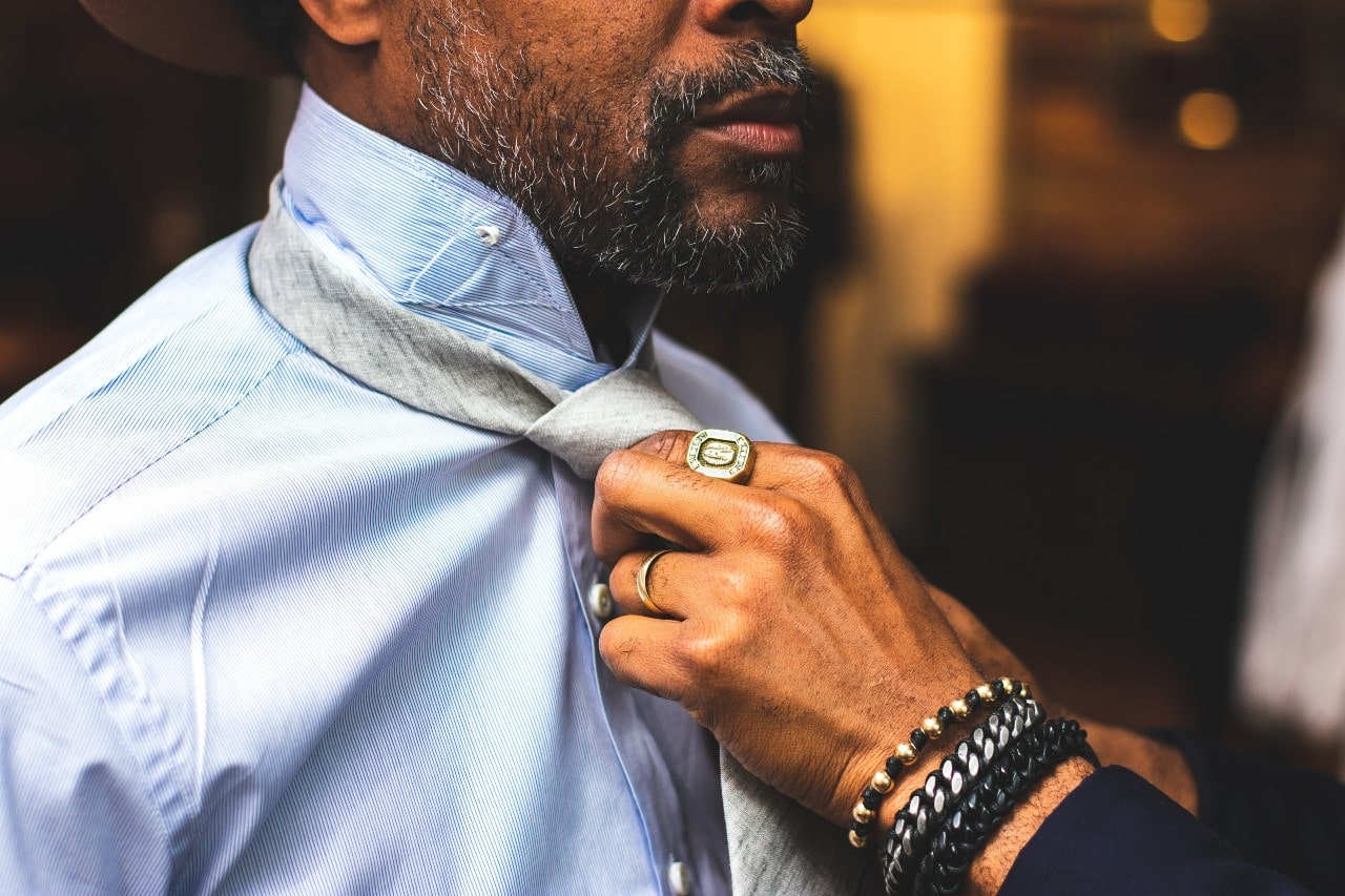 A fashionable dad ties his tie with three chic bracelets and a fashion ring