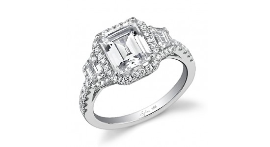 A three stone silver engagement ring by Sylvie with an emerald cut center stone