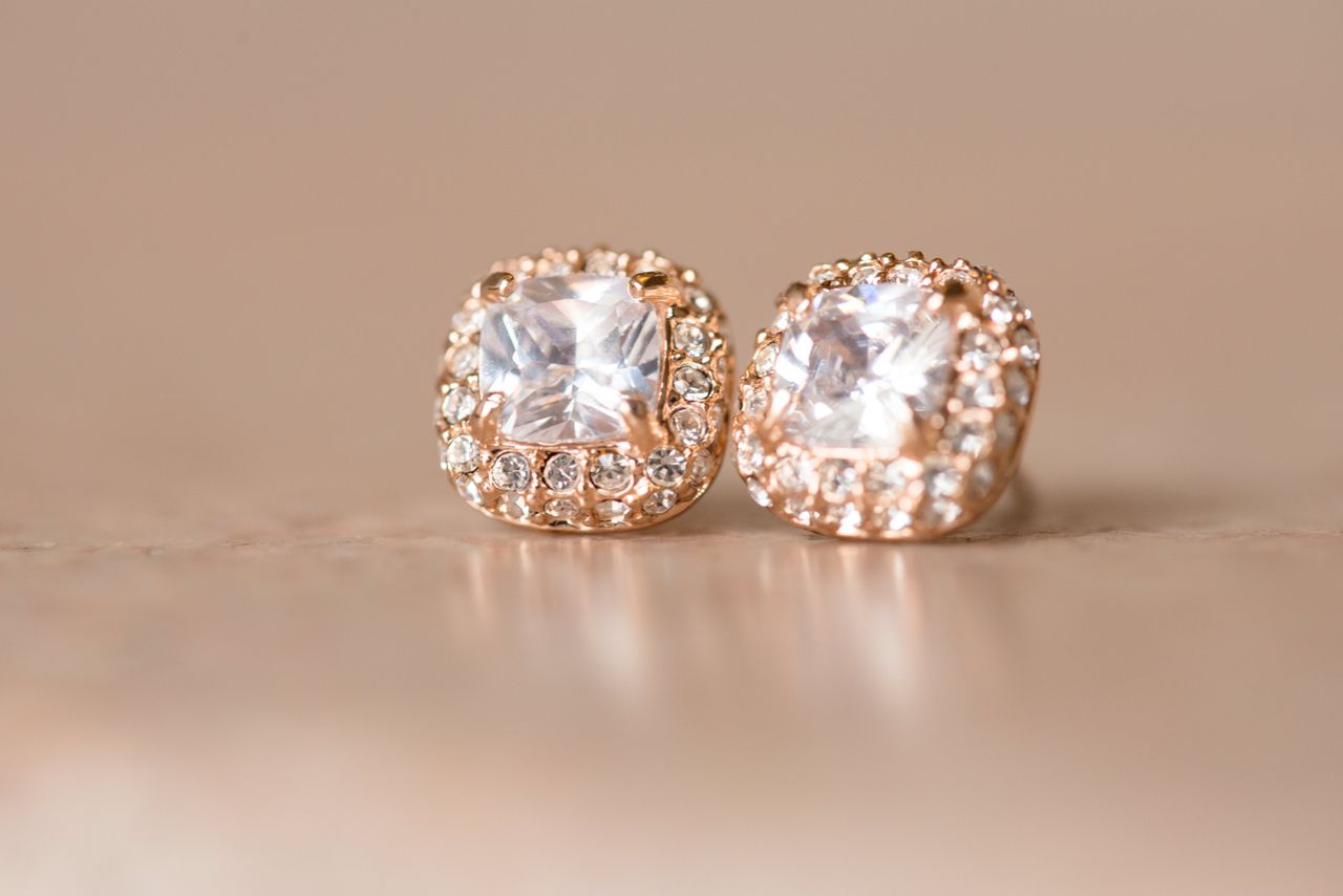 A close-up of opulent diamond stud earrings on a neutral background.