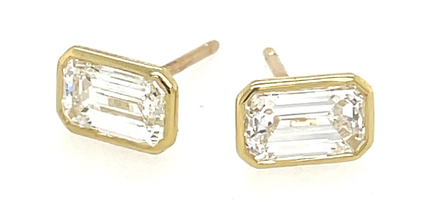 A pair of diamond stud earrings with gold bezels, available at Clarkes Jewelers.