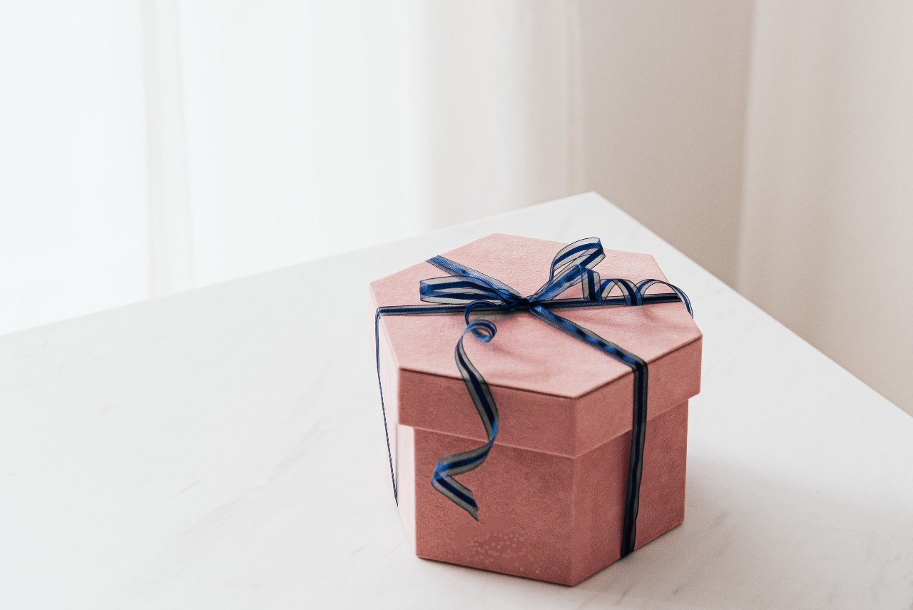 A colorful and elegant gift box sitting on a white tabletop.