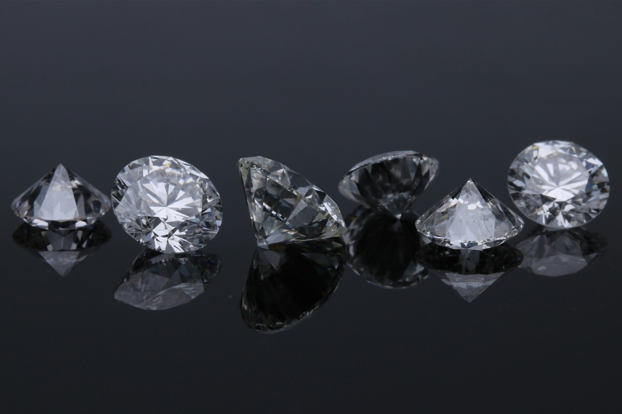 six round cut diamonds in a line on a dark reflective surface