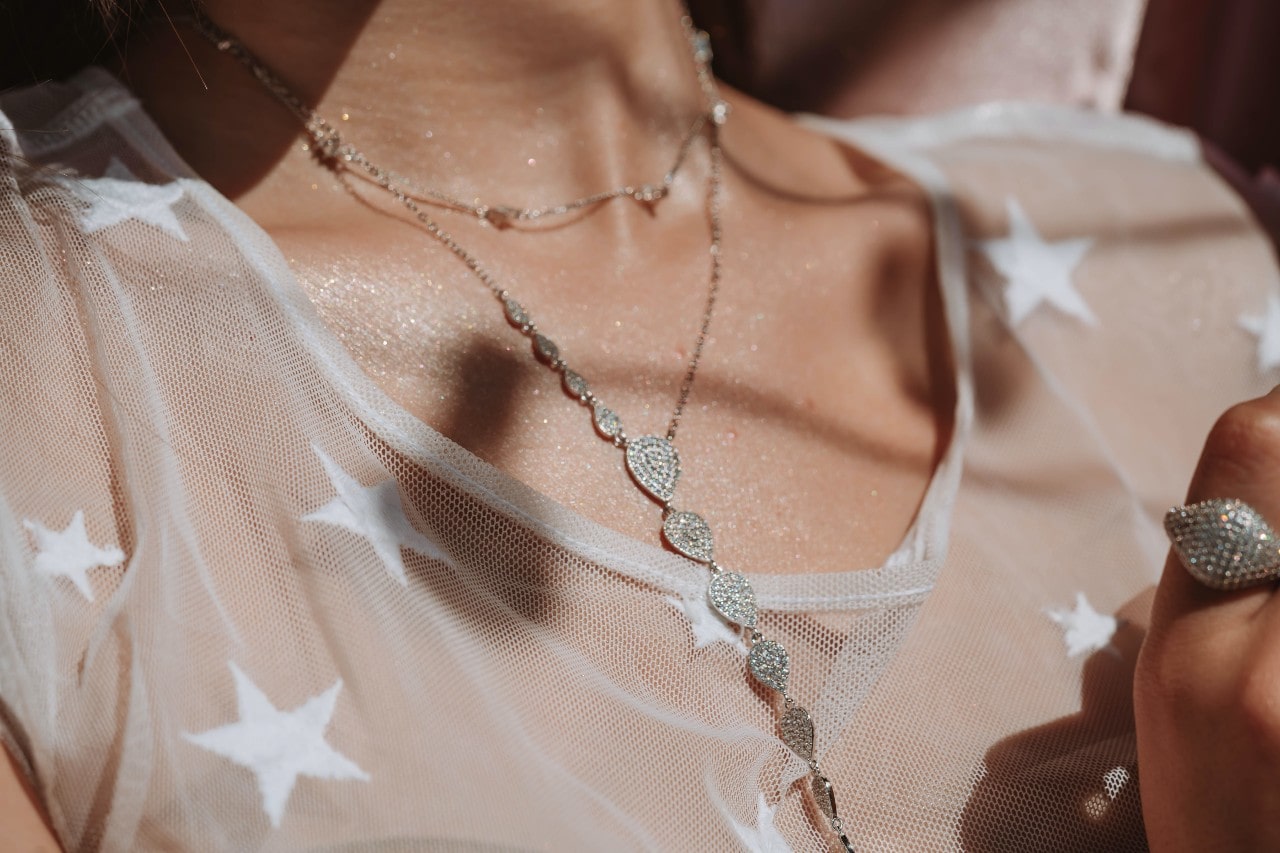 A woman wearing a delicate mesh top and bold diamond jewelry.