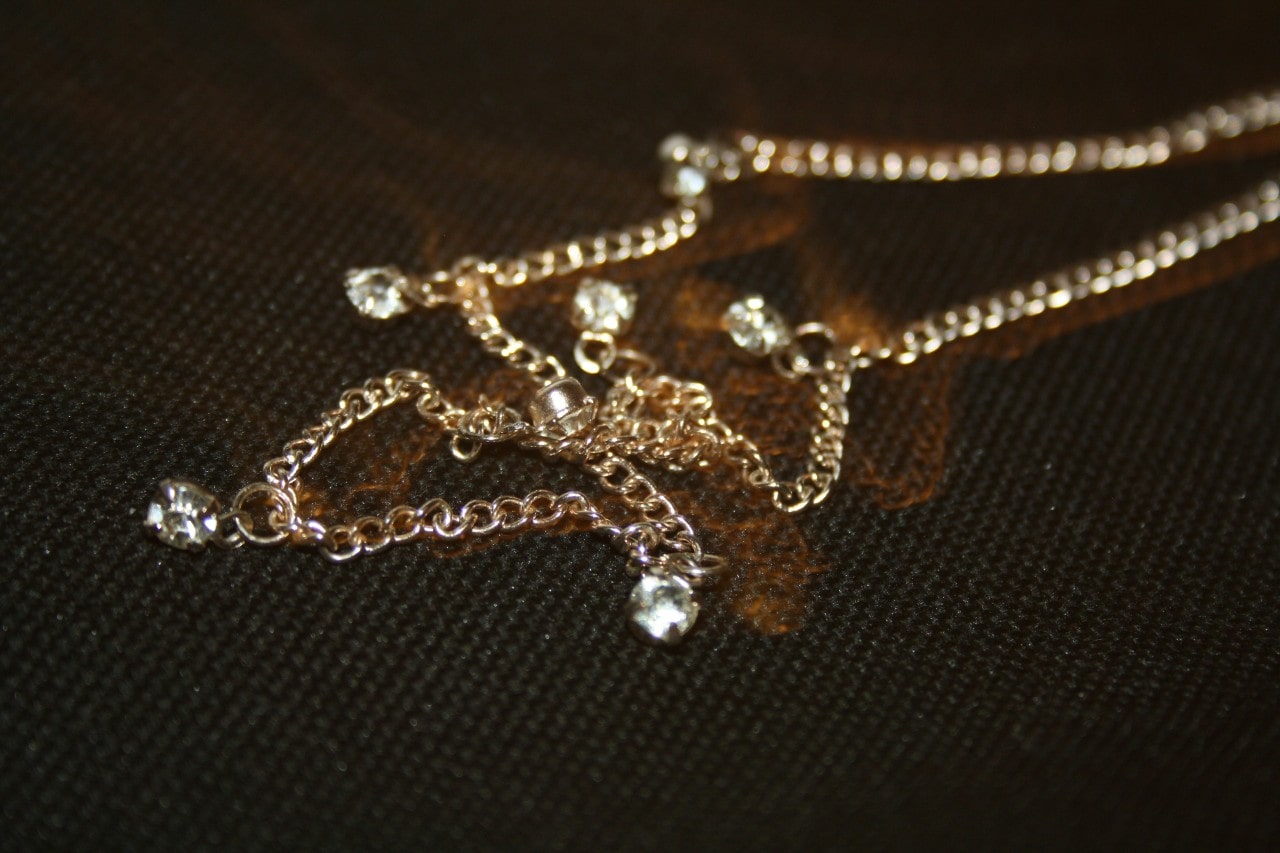 A diamond station necklace displayed on a textured black surface.