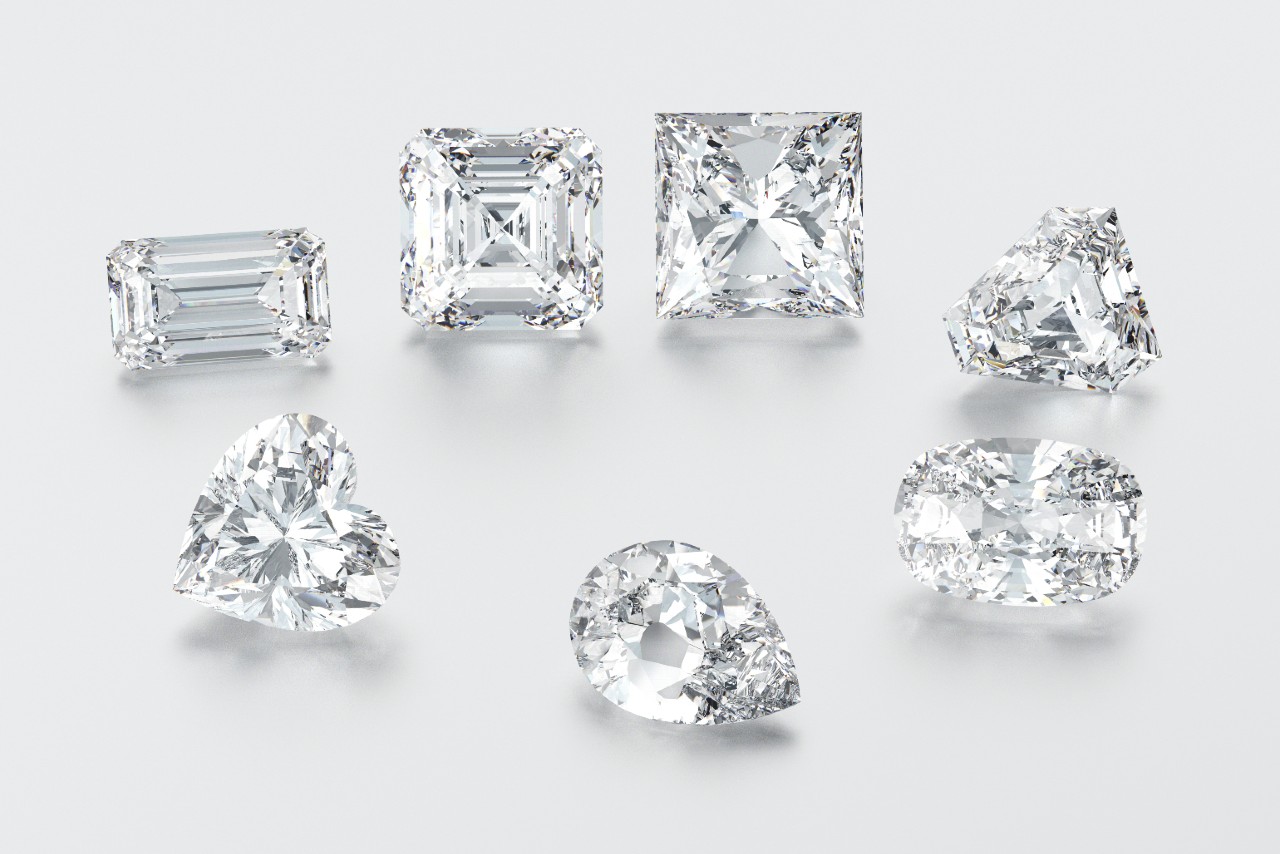 seven diamonds of different cuts in a an oval shape on a white surface.