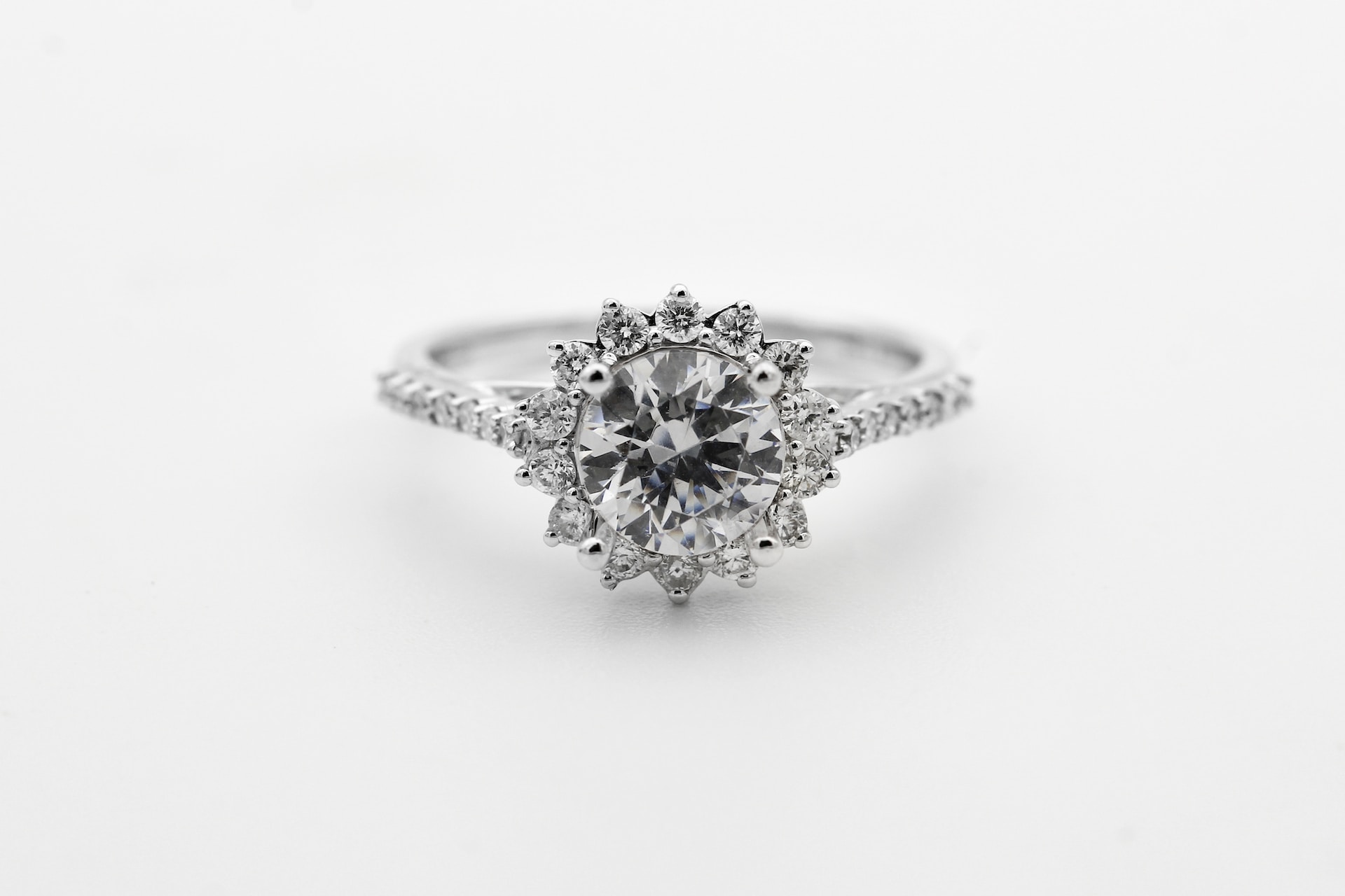 a round cut diamond halo engagement ring with side stones.