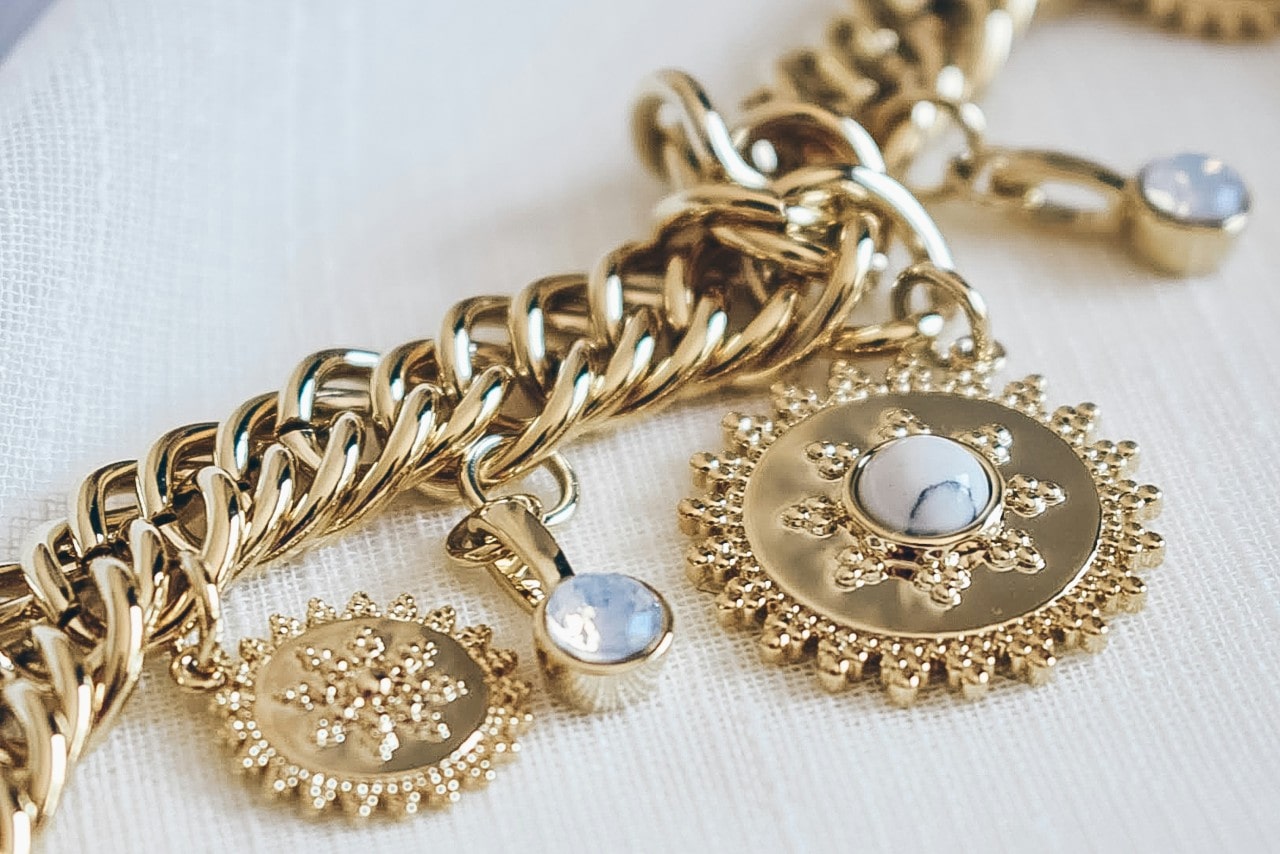 a yellow gold charm bracelet with sun motifs and gemstones