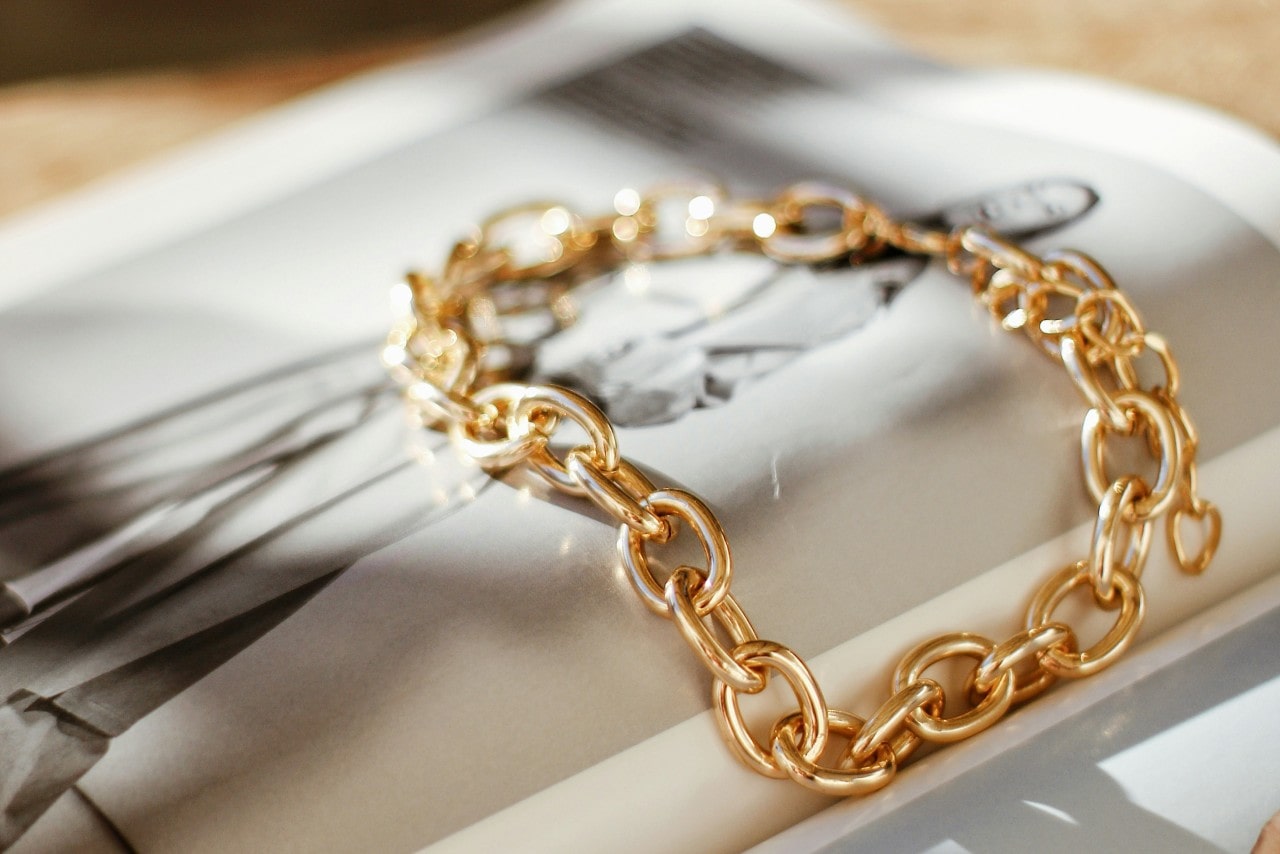 a chunky gold chain bracelet lying on an open magazine