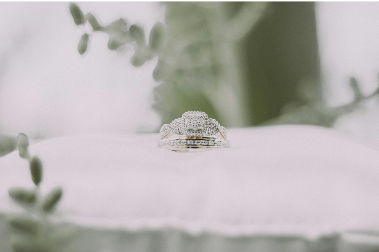 a matching wedding band and engagement ring with set with delicate details on a white pillow