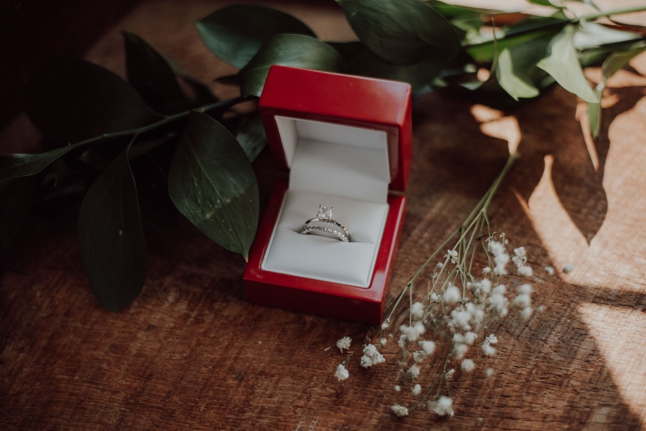 a matching engagement ring and wedding band set in a red ring box